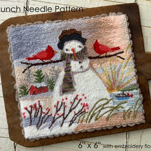 May include: A punch needle pattern featuring a snowman with two red cardinals perched on branches. The artwork, measuring 6" x 6", includes a winter landscape with a red barn and a snowy foreground. The text "Punch Needle Pattern" is at the top.