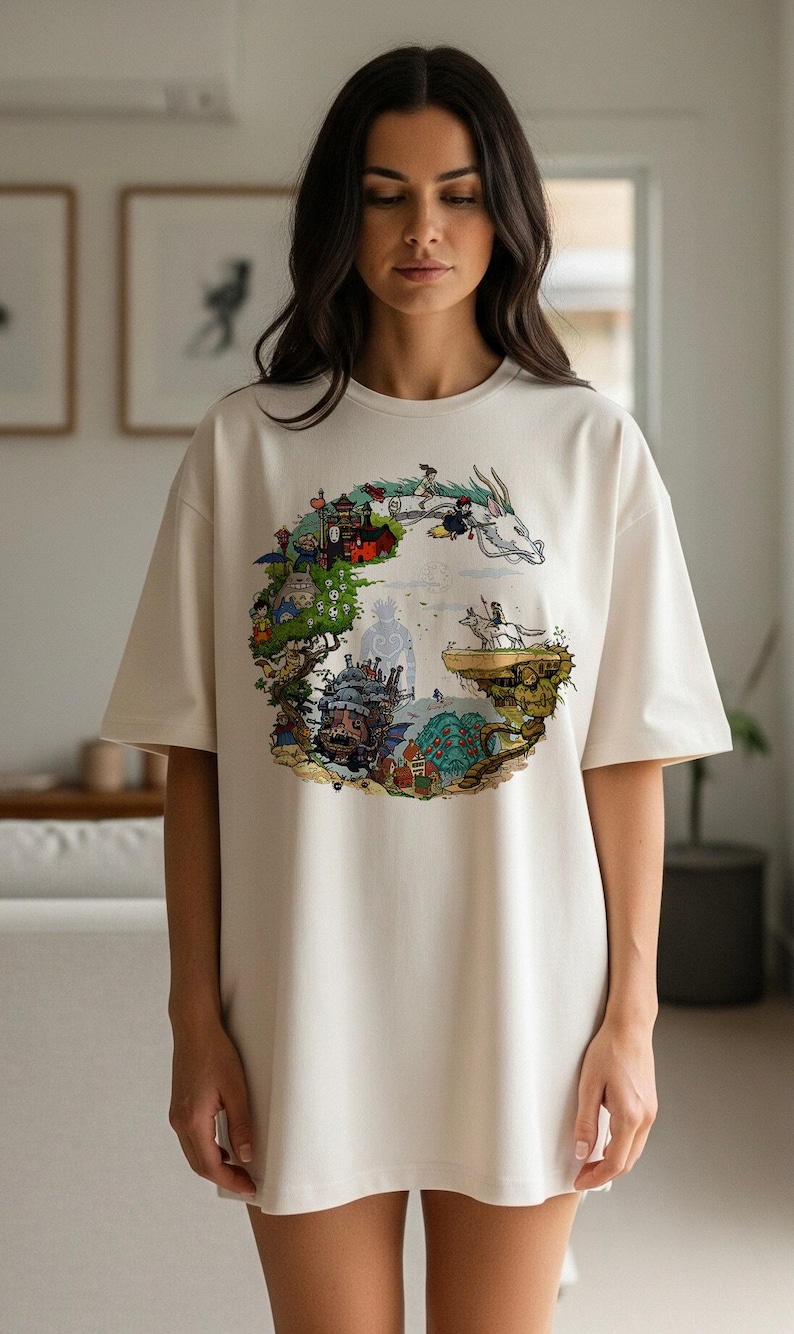 Pu&ograve; includere: T-shirt color crema con una grafica circolare colorata raffigurante personaggi e scene di un film d'animazione fantasy. Il design include un drago, un castello e altri elementi fantastici. La maglietta ha maniche corte e una vestibilit&agrave; ampia.