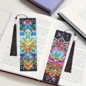 May include: Two decorative bookmarks with detailed, colourful mandala designs. Each bookmark has a beaded tassel and a decorative top. The bookmarks are on an open book, highlighting their use as reading accessories.