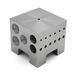 May include: A silver metal cube with various sized holes drilled into its sides. The cube has a flat top with a single small hole and is supported by four short legs. The metal has a brushed finish.
