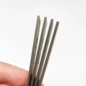 Può includere: Quattro lame in metallo argentato con la scritta "WS-2" stampata su ogni lama.