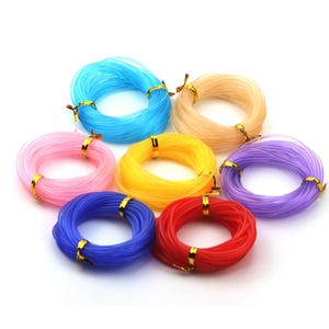 May include: Seven circular coils of flexible, translucent plastic cord in assorted colours including blue, light blue, pink, yellow, beige, purple, and red. Each individual coil is secured with a small, shiny gold-coloured metallic fastener.