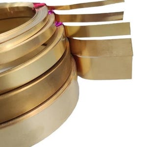 May include: A stack of gold-coloured metal strips, with the top strip folded over to show the width. The strips are arranged in a graduated size, with the largest strip at the bottom and the smallest strip at the top.