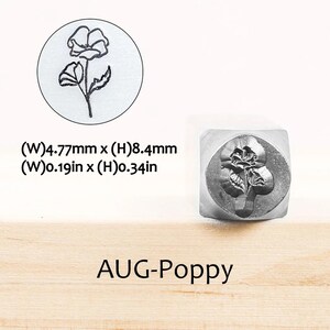 Pode incluir: Um carimbo de metal com um desenho de flor de papoula. O carimbo tem 4,77 mm de largura e 8,4 mm de altura. O texto "AUG-Poppy" est&aacute; abaixo do carimbo. Uma imagem circular da flor de papoula tamb&eacute;m &eacute; mostrada.