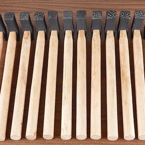 May include: A row of ten hammers, each with a light wooden handle and a black, textured head. The hammers are displayed to show the different patterns on the striking faces. The handles are smooth and cylindrical.