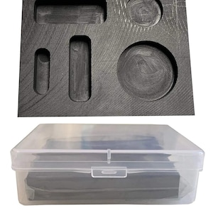 Puede incluir: Un inserto de espuma gris oscuro con varios recortes con formas, incluidos rectángulos y círculos, se encuentra encima de un recipiente de almacenamiento de plástico transparente. El recipiente tiene una tapa a presión y parece contener insertos de espuma adicionales.