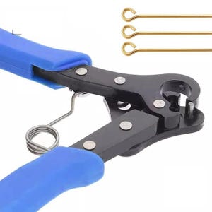 May include: A pair of pliers with blue rubberized handles, a black metal head, and a silver tension spring. Three thin gold-colored metal eye pins with circular loops at one end are positioned horizontally above the pliers in the upper right corner.