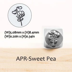 Pode incluir: Um carimbo de metal com um desenho de flor de ervilha-de-cheiro. O carimbo mede 5,08 mm de largura e 8,4 mm de altura. O texto "APR-Sweet Pea" est&aacute; abaixo. &Eacute; mostrada uma imagem de perto da flor.