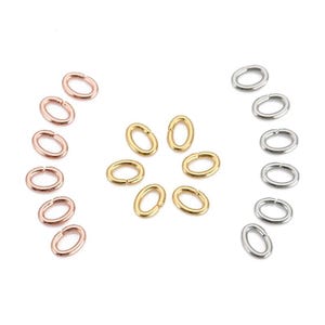 May include: An assortment of oval jump rings in rose gold, gold, and silver. The rings are displayed on a white background, highlighting their metallic finish. These jewellery findings are suitable for crafting and jewellery making.