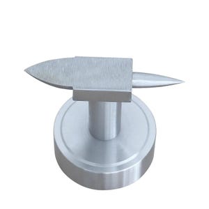 May include: A small, silver anvil with a flat top and a pointed horn. It is mounted on a round base with a cylindrical support. The metal has a brushed finish. The anvil is approximately 10 cm in height.