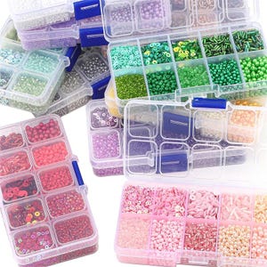 May include: A collection of clear plastic storage containers filled with various beads, sequins, and embellishments in a range of colors, including pink, red, green, and purple. The containers are organized into compartments, ideal for crafting and jewelry making.