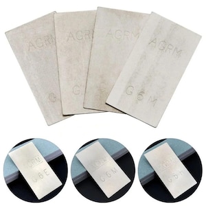 May include: Four rectangular, light grey abrasive stones with the text "AGRM" and "G6M" or "G6E" or "G6H" etched on the surface. The stones are arranged in a fan shape, with three additional circular images of the stones.