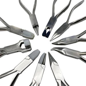 May include: A selection of metal pliers in a circular arrangement. The pliers have different head shapes, including pointed, flat, and curved, with some featuring rubber or plastic grips. The tools are silver in colour and appear unused.
