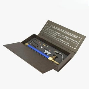 May include: A welding tool kit presented in a brown box. The kit contains a blue and brass torch, plus several nozzles and attachments. The box features Chinese text. The tools are neatly arranged within the open box.