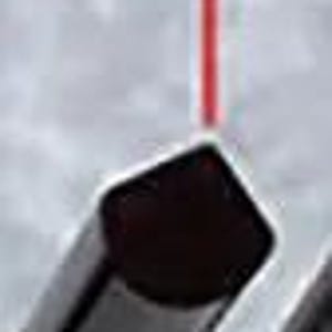 May include: A close-up of a silver metal object with a red laser beam pointing at it. The object is labeled "105&deg;".
