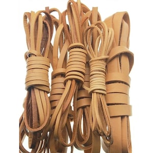 Può includere: Quattro fasci di strisce di cuoio color marrone chiaro, ciascuno arrotolato e fissato con un avvolgimento dello stesso materiale. Le strisce presentano una finitura liscia e opaca e un colore marrone chiaro naturale, con una consistenza uniforme.