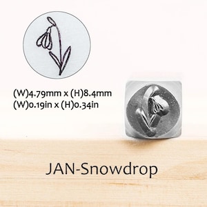 Pode incluir: Um carimbo de metal com um desenho de flor de neve, medindo 4,79 mm de largura e 8,4 mm de altura. O carimbo est&aacute; em um recipiente de pl&aacute;stico transparente. O texto "JAN-Snowdrop" est&aacute; abaixo.