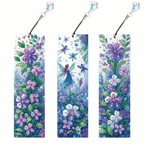 Puede incluir: Tres marcapáginas decorativos con diseños florales y de hadas. Cada marcapáginas tiene una ilustración diferente de flores, hadas y mariposas en tonos morados, rosas y verdes. Cada marcapáginas tiene un dije de cristal adjunto.