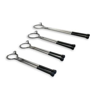 May include: Four metal tongs with a circular end and black handles are arranged diagonally on a white background. The tongs have a silver-colored shaft and a loop at the end opposite the handle. The handles are black and have a rounded end.