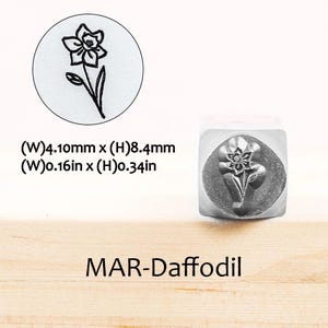 Pode incluir: Um carimbo de metal com um desenho de narciso. O carimbo tem 4,10 mm de largura e 8,4 mm de altura. O texto "MAR-Daffodil" est&aacute; abaixo do carimbo. Uma imagem circular do narciso tamb&eacute;m &eacute; mostrada.