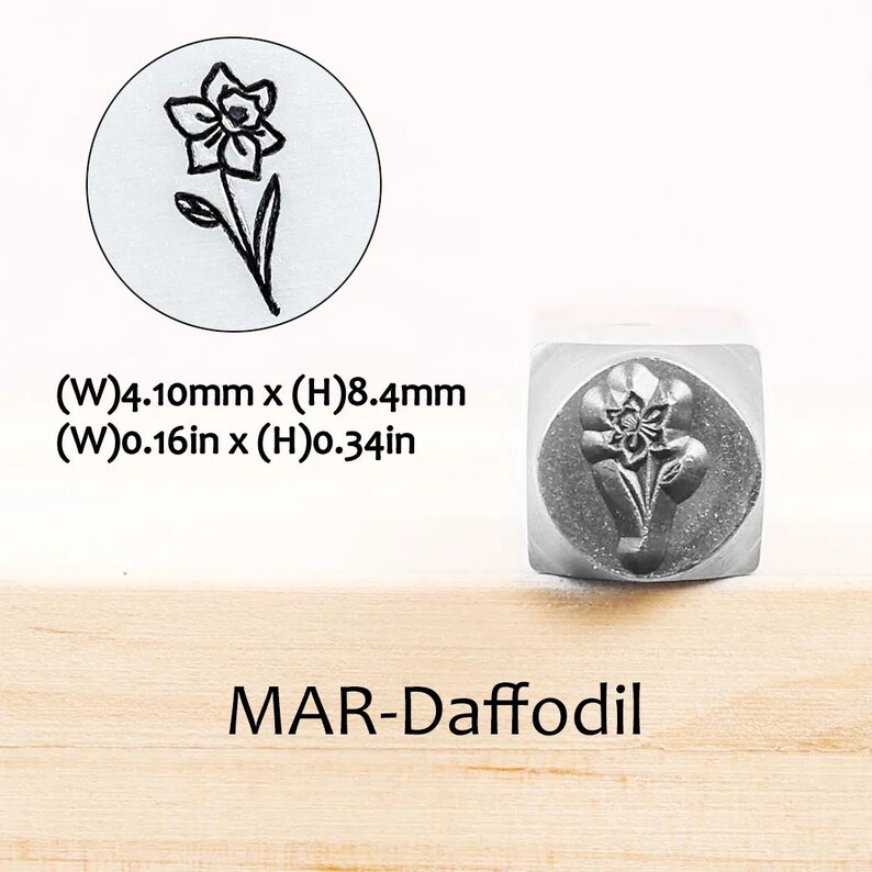 Pode incluir: Um carimbo de metal com um desenho de narciso. O carimbo tem 4,10 mm de largura e 8,4 mm de altura. O texto "MAR-Daffodil" est&aacute; abaixo do carimbo. Uma imagem circular do narciso tamb&eacute;m &eacute; mostrada.