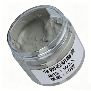 May include: A clear plastic jar filled with a thick, grey diamond polishing paste. A white label on the side features black text that reads: 金刚石研磨膏, 规格: W3.5, 重量: 50克. The paste has a smooth, viscous texture and fills the container to the top.