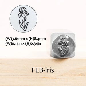 Pode incluir: Um carimbo de metal com um desenho de flor de &iacute;ris. O carimbo tem 3,61 mm de largura e 8,4 mm de altura. O texto "FEB-Iris" &eacute; exibido abaixo do carimbo.