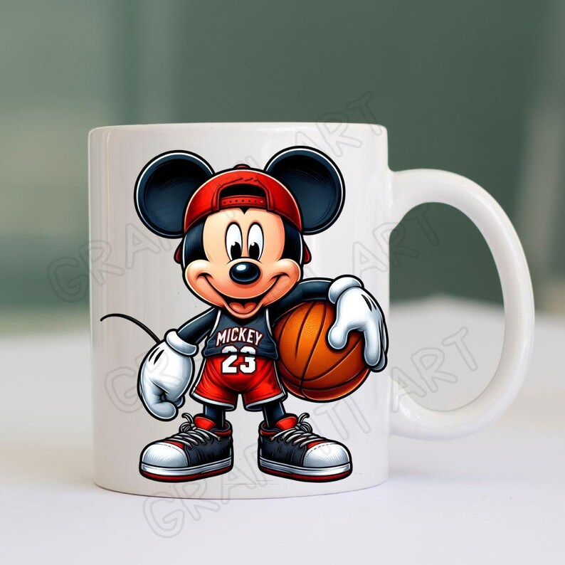 Peut inclure: Une tasse en c&eacute;ramique blanche avec une image de dessin anim&eacute; de Mickey Mouse portant un maillot de basket-ball rouge avec le num&eacute;ro 23 et tenant un ballon de basket. Le texte "Mickey" est sur le maillot.