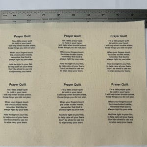 Peut inclure: Une courtepointe de prière en tissu beige avec le texte "Prayer Quilt" et un poème sur le but de la courtepointe. Le poème dit : "Je suis une petite courtepointe de prière à tenir dans votre main. Je vous aiderai lorsque des problèmes surviendront, ces choses que vous n'avez pas prévues. Lorsque vos doigts touchent la croix cachée à l'intérieur, souvenez-vous que Dieu est toujours à vos côtés. Tenez-moi bien serré dans votre poing, pour vous aider à calmer toutes vos peurs. N'ayez pas peur de m'utiliser pour essuyer vos larmes."