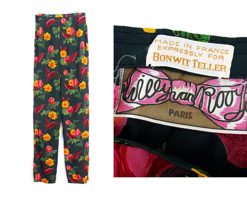 Puede incluir: Pantalones negros con estampado floral con flores rojas, amarillas y naranjas. Los pantalones est&aacute;n colgados de una percha blanca. La etiqueta dice "Made in France expressly for Bonwit Teller" y "Willy van Rooy Paris."