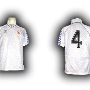 Puede incluir: Camiseta de f&uacute;tbol blanca con un patr&oacute;n texturizado, detalles azules y el n&uacute;mero 4 en la espalda. La camiseta tiene cuello y un logo del equipo. Las mangas tienen rayas azules y blancas.