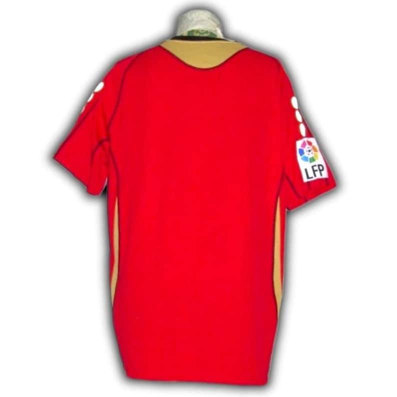 May include: Red short-sleeved jersey with gold trim and a gold collar. The jersey has white accents on the sleeves and the LFP logo on the right sleeve. The jersey is made of a smooth, likely synthetic material.