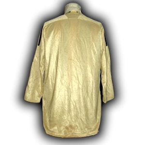 K&ouml;nnte beinhalten: Ein lang&auml;rmeliges, hellgelbes Hemd mit schwarzen Streifen auf den Schultern. Das Hemd hat einen hohen Kragen mit einem gr&uuml;n-gelben Design. Der Stoff scheint leicht strukturiert und gl&auml;nzend zu sein.