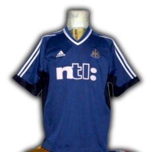 May include: A navy blue soccer jersey with white accents and the text "ntl:" across the front. The jersey has a V-neck collar and white stripes on the sleeves. The Adidas logo is visible on the upper chest.