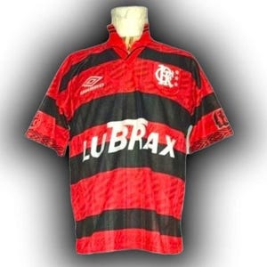 May include: Red and black striped football shirt with the word "LUBRAX" in white across the front. The shirt has a v-neck collar and short sleeves. The Umbro logo is visible on the upper left chest.