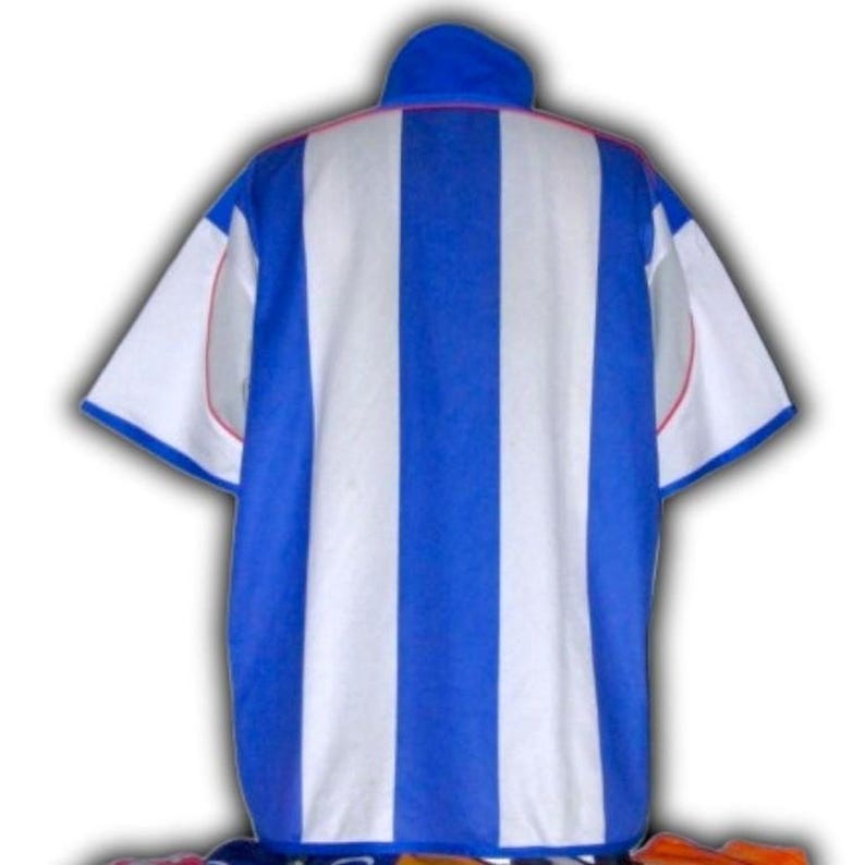 May include: A blue and white striped jersey with a blue collar and white sleeves. The jersey has a vertical stripe pattern and red trim around the collar and sleeves. The jersey is likely for a sports team.