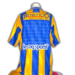 May include: A blue and yellow soccer jersey with the word "BENEFICIO" across the top and "le coq sportif" at the bottom. The jersey has blue and yellow vertical stripes and a blue patterned design.