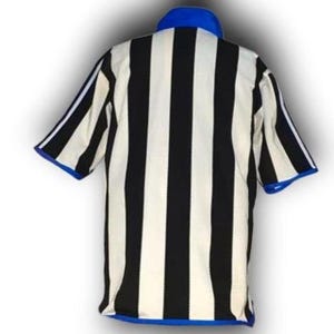 Op de afbeelding: Een gestreept scheidsrechtershirt in zwart en wit, met een blauwe kraag en mouwboorden. Het shirt heeft korte mouwen en is ontworpen voor sportofficials. De stof lijkt licht van gewicht.