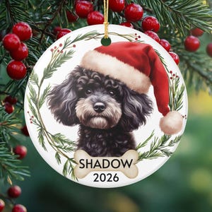 Gepersonaliseerd keramisch ornament van een zwarte Cavapoo, met afbeelding van een kerstmuts, matte afwerking, gepersonaliseerde naam en jaartal.