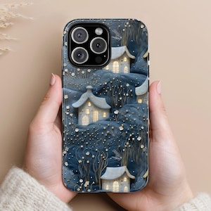 May include: A blue and white phone case with a wintery scene of houses and trees. The case has a cutout for the camera lens and a raised lip around the edges to protect the screen.