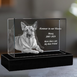 May include: A glass memorial cube with a black base, featuring a 3D engraved image of a German Shepherd dog. The inscription reads "Forever in our Hearts, Maxx, 2007-2024, More than a pet, My Best Friend."