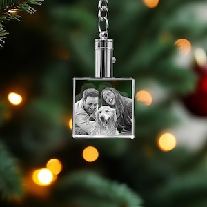 Könnte beinhalten: Ein silberner Schlüsselanhänger mit einem quadratischen Kristallanhänger, der ein Schwarzweißfoto eines Paares und seines Hundes zeigt. Der Anhänger hängt an einer silbernen Kette.