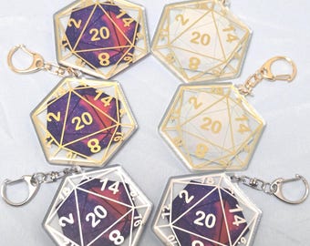 May include: Six dodecahedron-shaped keychains with gold or silver-colored metal accents. The dice feature a galaxy design with the number 20 prominently displayed. The numbers 2, 8, 14, and 16 are also visible. Each keychain has a clasp for easy attachment.