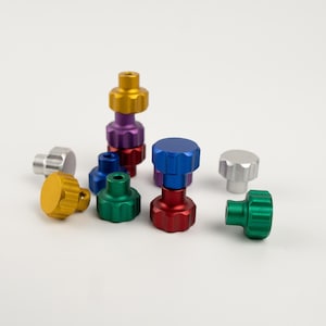 以下が含まれることがあります： 様々な形とサイズのカラフルな金属製のノブの詰め合わせ。ノブはアルミニウム製で、磨かれた仕上げになっています。色は、ゴールド、シルバー、パープル、ブルー、グリーン、レッドなどがあります。