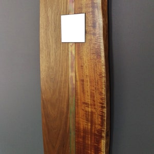May include: A wooden wall art piece with a live edge and a copper strip down the center. A white square is attached to the copper strip.