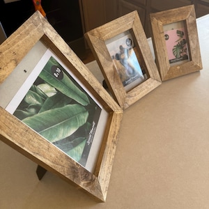 May include: Three wooden picture frames with a rustic brown finish. The largest frame is 8x10 inches and features a print of green leaves. The other two frames are smaller and have blank white inserts.