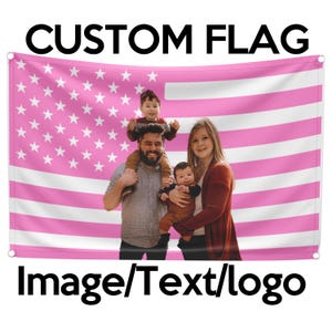 May include: A pink and white American flag with a family of four in front of it. The family is made up of two adults and two children. The adults are smiling and the children are looking at the camera. The flag is hanging on a wall.