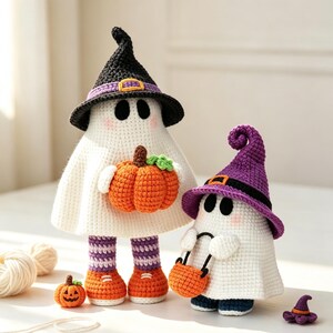 May include: Two crocheted ghost figures. The larger ghost wears a black witch hat with a purple band and holds an orange pumpkin. It has striped purple and white legs and orange shoes. The smaller ghost wears a purple witch hat and carries an orange bucket.