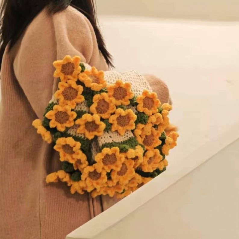 K&ouml;nnte beinhalten: Ein geh&auml;keltes Schals in Sonnenblumenform mit gelben und gr&uuml;nen Blumen. Der Schal ist aus Garn gefertigt und ein einzigartiges und stilvolles Accessoire.