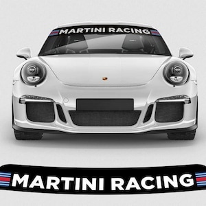Op de afbeelding: Een witte sportwagen met de tekst "MARTINI RACING" bovenaan de voorruit. De tekst is wit met blauwe, rode en zwarte strepen. Een bijpassende sticker staat onderaan de afbeelding.